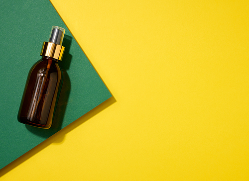 brown glass bottle with spray on yellow green background, top view. Cosmetics SPA branding mockup