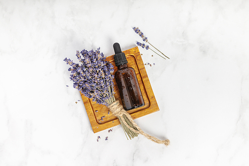 Flat lay composition with lavender flowers and essential oil on white marble background