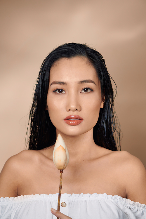 Young beautiful Asian women holding dried lotus buds on beige background