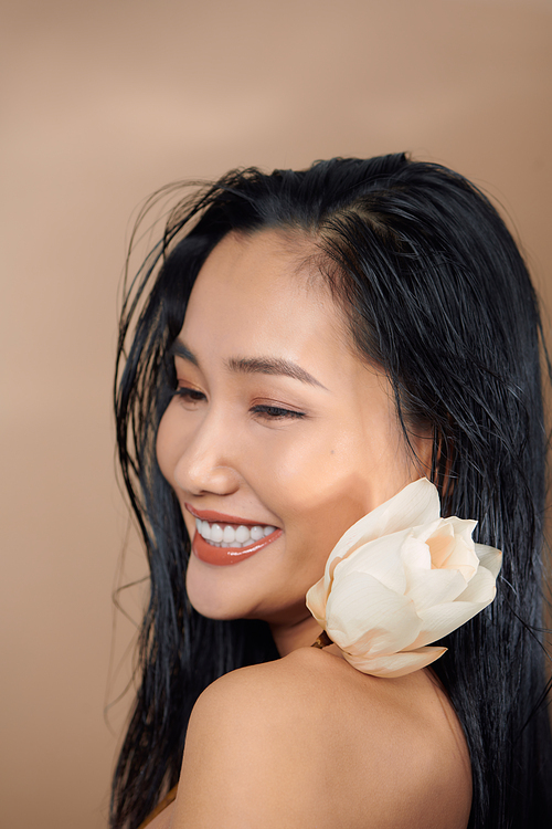 Tanned woman in white cropped top holding dried lotus buds