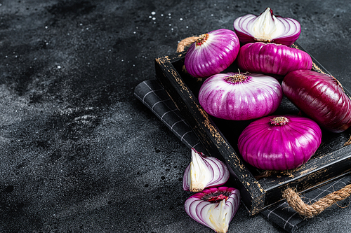 Flat red sweet onion in a wooden tray. Black background. Top View. Copy space.