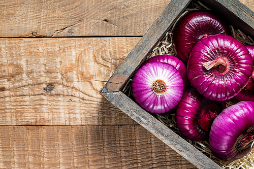 Flat red sweet onion in wooden box. Wooden background. Top View. Copy space.
