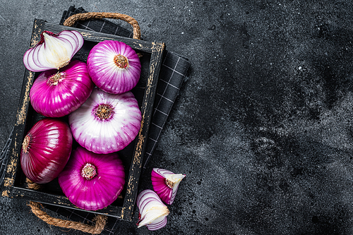 Flat red sweet onion in a wooden tray. Black background. Top View. Copy space.