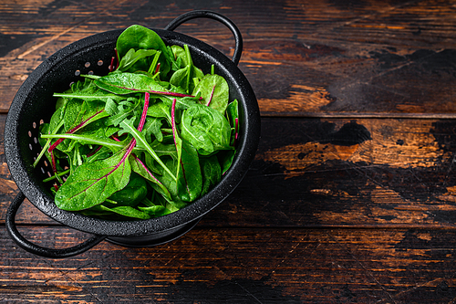 Fresh raw mixed greens, spinach, swiss chard and arugula. Dark wooden background. Top view. Copy space.