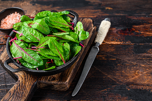 Fresh raw chard leaves,  mangold, swiss chard in a pan. Dark Wooden background. Top view. Copy space.