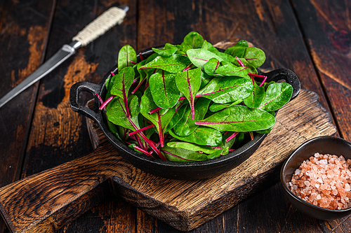 Fresh raw chard leaves,  mangold, swiss chard in a pan. Dark Wooden background. Top view.