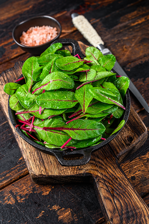 Fresh raw chard leaves,  mangold, swiss chard in a pan. Dark Wooden background. Top view.