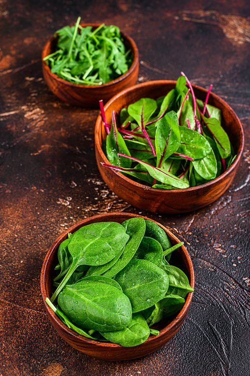 Mix Salad leafs, Arugula, Spinach and swiis Chard in wooden bowls. Dark background. Top view.