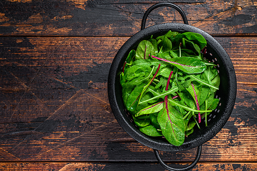 Fresh raw mixed greens, spinach, swiss chard and arugula. Dark wooden background. Top view. Copy space.