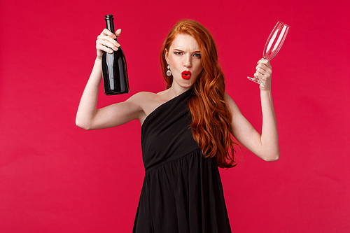 Celebration, holidays and women concept. Sassy and carefree, excited young redhead woman having fun at party, raising bottle of champagne and glass, inviting everyone for drink, look daring.
