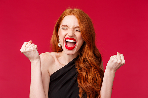 Celebration, emotions and beauty concept. Close-up portrait of pretty young elegant redhead woman feel like champion, scream yes or hooray with clenched fists, tirumphing, celebrating.