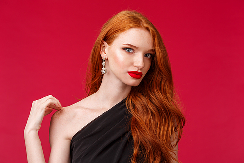 Romance, elegance, beauty and women concept. Close-up portrait of sensual attractive european woman with long curly ginger hair, bare shoulder touching gently, wear black evening dress.