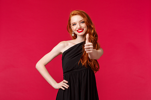 Fashion, luxury and beauty concept. Portrait of assured and pleased young redhead woman in elegant black dress, show thumb-up in approval or like sign, agree or guarantee good quality.