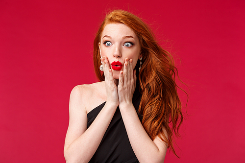 Makeup, beauty and women concept. Close-up portrait of amazed and impressed young redhead beautiful girl seeing something awesome and expensive, want it, stare astonished, standing red background.
