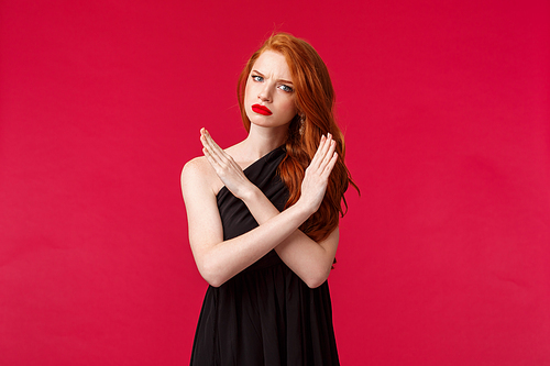 Fashion, luxury and beauty concept. Portrait of serious and displeased, mad young sassy redhead girl in black dress, making cross stop sign, grimacing with disapproval, disagree and reject.