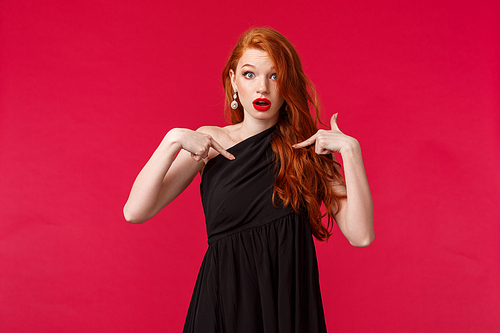 Fashion, luxury and beauty concept. Portrait of concerned and worried young redhead woman in makeup, wearing black dress, pointing herself shocked and nervous, being picked or accused.