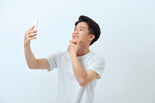 A portrait of a young attractive man taking pictures of him self (selfie) with smartphone