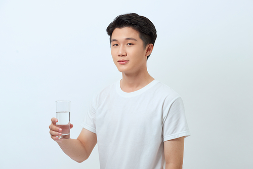 A happy man in a white T-shirt holds a mug of water in his hand