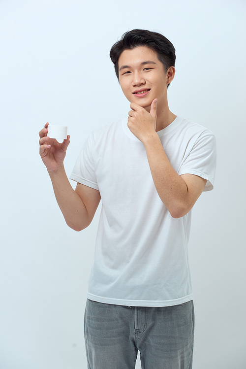 Young man holding cosmetic container face cream isolated on white