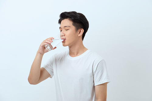 Attractive young man is drinking water from a glass.