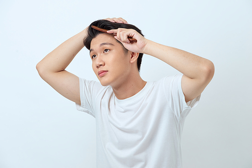Portrait of handsome cheerful young man combing his hair