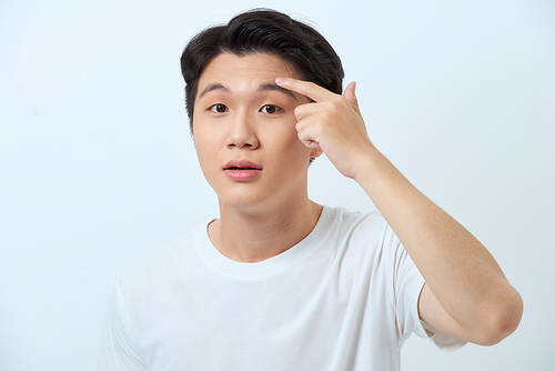 Young man squeezing a pimple, men's skincare concept