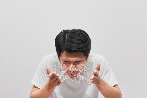Handsome man is washing up, splash of water, on white background