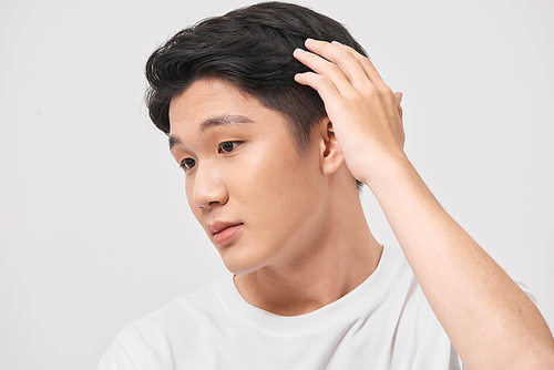 Young handsome man wearing white t-shirt over isolated background Smiling confident touching hair with hand up gesture, posing attractive