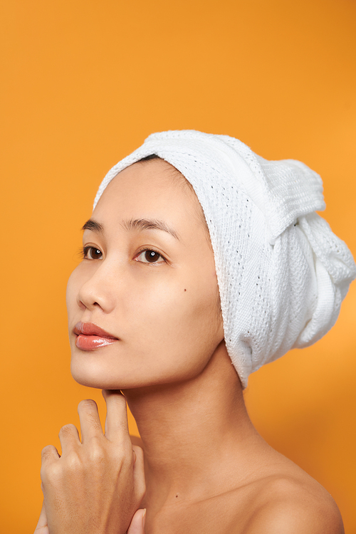 Spa skin care beauty woman wearing hair towel after beauty treatment. Beautiful young woman with perfect skin isolated on orange background.