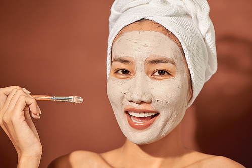 Spa Woman applying Facial clay Mask. Beauty Treatments.