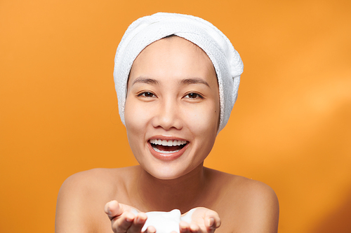 Cheerful Asian female holding foaming cleanser, has clean fresh healthy skin