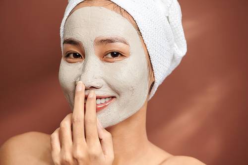 Young woman wearing clay mask on her face