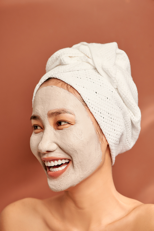 Emotional portrait of a happy and positive beautiful nude young woman with a clay cosmetic mask on her face