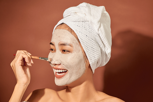 Young beautiful woman with clay mask on her face. Salon skin care, natural cream of algae.