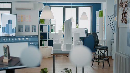 Empty architectural office with building model and blueprints plans on table. Nobody in space used for real estate design and development with architecture construction structure.