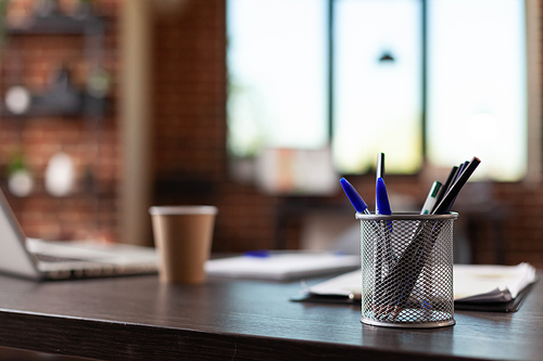 Close up of office equipment and instruments on desk in empty business space. Nobody in startup office with pens and pencils on wooden table, used to do financial paperwork for company.