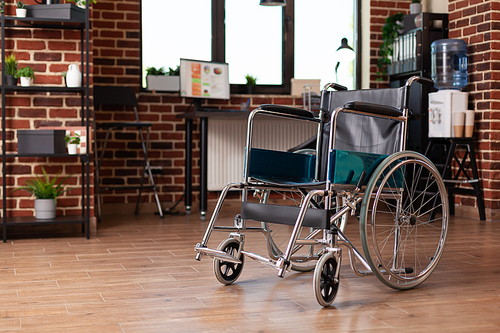 Wheelchair in empty business office with equipment. Nobody in startup space with supplies, decorations and chair used by people with disability. Modern decor in company workplace