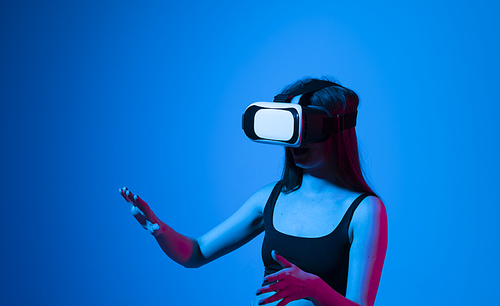 Smile happy woman getting experience using vr-headset glasses of virtual reality much gesticulating hands on gray background. Girl spend shes time in metaverse