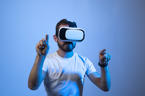 Future technology, gaming, entertainment and people concept - happy young man with virtual reality headset or 3d glasses playing video game in metaverse