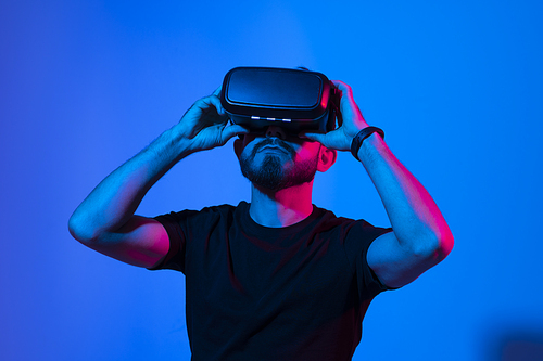 Bearded man in virtual reality headset communicate with a friends in a metaverse. Young man playing a vr video game