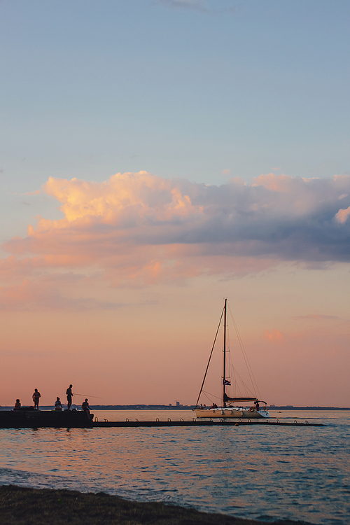 Yacht sailing against sunset. Holiday lifestyle landscape with skyline sailboat and two seagull. Yachting tourism - maritime evening walk. Romantic trip on luxury yacht during the sea sunset.