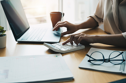 Close up woman using computer calculating finance or taxes on machine, female manage home family expenditures, using calculator, make payment on laptop.