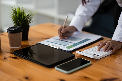 Businesswoman inspecting and checking the business reports graphs to audit the financial reports by calculating the results. Analyzing the revenue and auditing the budget concept.