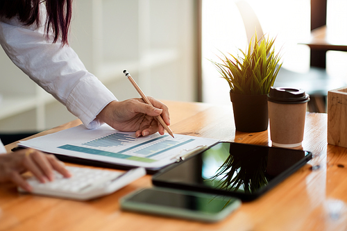 Businesswoman inspecting and checking the business reports graphs to audit the financial reports by calculating the results. Analyzing the revenue and auditing the budget concept.