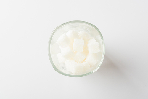 Top view glass full of white sugar cube sweet food ingredient, studio shot isolated on white background, health high blood risk of diabetes and calorie intake concept and unhealthy drink