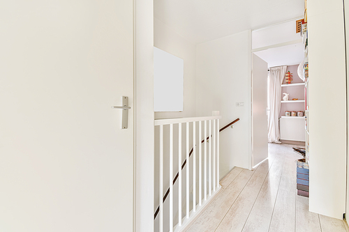 Closed white room door next to the top of the stairs of the house