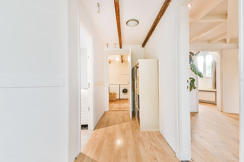 Long white corridor leading with many doors and a laundry room at the end