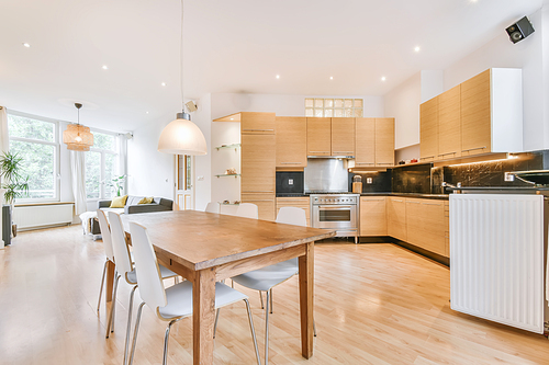 Home interior design of modern loft apartment with open kitchen in minimalist style and spacious dining zone with table and chairs