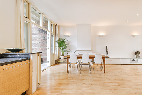 Home interior design of modern loft apartment with open kitchen in minimalist style and spacious dining zone with table and chairs