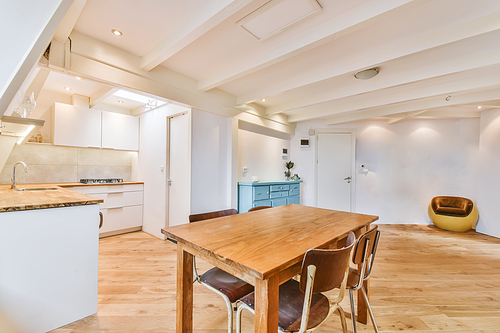 Home interior design of modern loft apartment with open kitchen in minimalist style and spacious dining zone with table and chairs